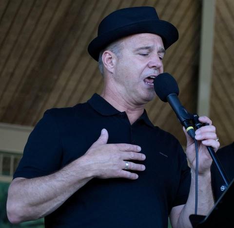 Man in a crooner hat singing into a microphone